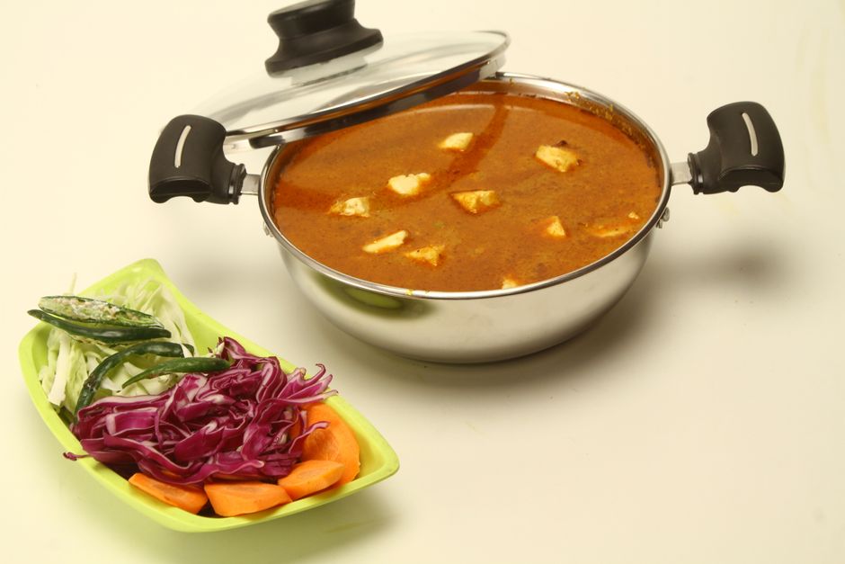 A flavorful Indian curry with tofu and fresh vegetables served in a stainless steel pot.