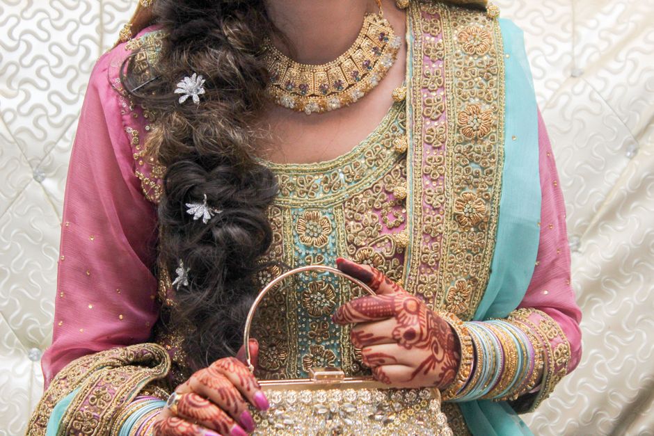 Close-up of an Indian bride showcasing traditional clothing and henna with ornate jewellery.